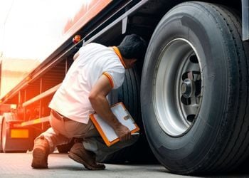 Commercial truck driver performing safety inspection on transportation vehicle