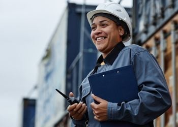 Professional female safety manager in hard hat reviewing safety protocols at industrial site