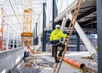 Safety supervisor in high-visibility gear conducting site inspection at construction project