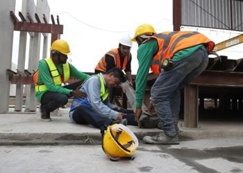Construction workers assisting injured colleague on site for workplace injury and WCB claim management