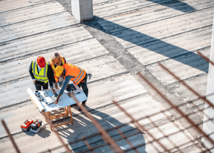 Construction workers in safety gear working on rooftop project requiring interim safety management oversight