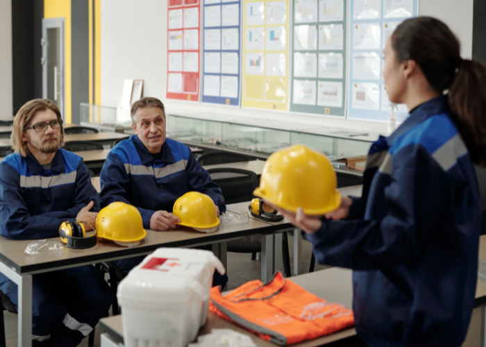 Safety training participants in hard hats and high-visibility vests learning hands-on safety procedures