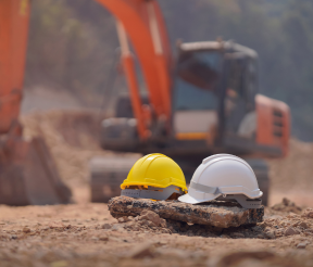 Construction hard hats and safety equipment at active building site with excavator