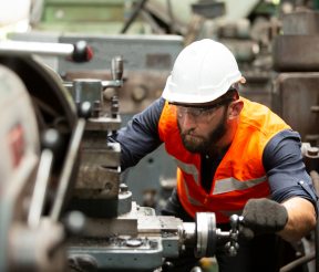 Manufacturing worker in safety gear operating industrial equipment on production floor