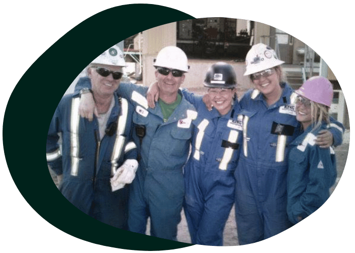 Hutton Safety Group team members in blue coveralls and safety helmets smiling together at a worksite